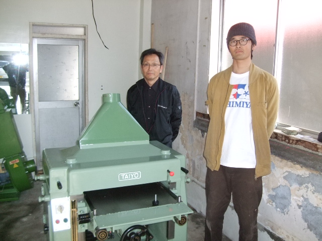 丸山農園工作室の代表丸山博亮さん（右）と今回ご購入頂いた機械のうちの一つ、太洋のプレナーの前で