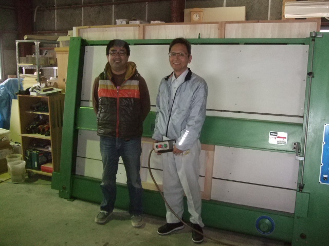 パイン家具工房　バックヤードの代表、杉本力彦さん（左）と当社秋山とお買い上げ頂いた組み立て機の前で。